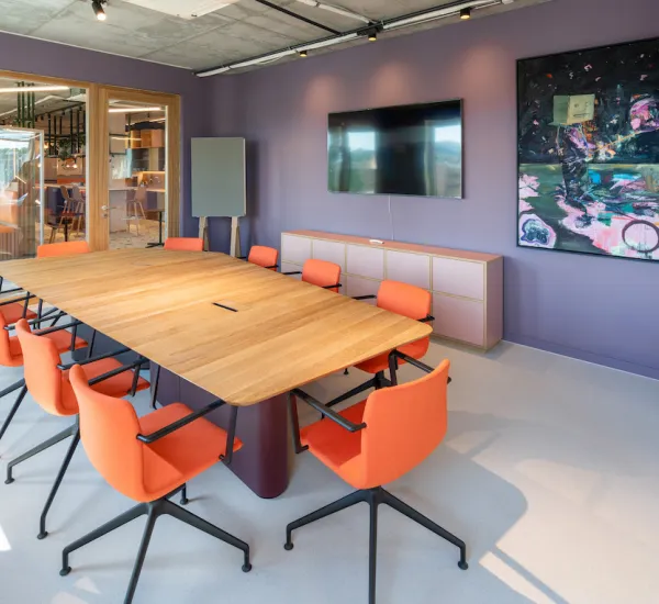 Picture of a large meeting table with orange chairs around